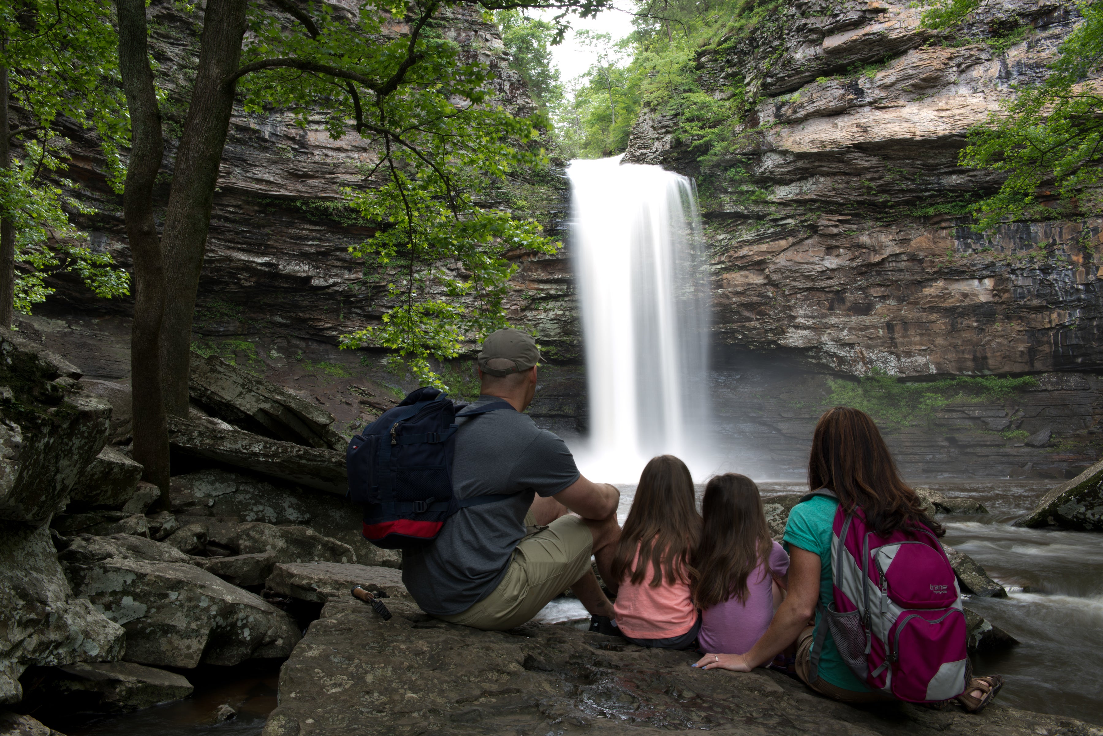 A man, woman, and two children looking at the waterfall at Petit Jean State Park